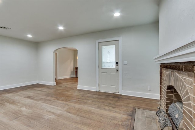 2524 NW 15th St, Oklahoma City, OK 73107 - unfurnished living room featuring arched walkways, wood finished floors, recessed lighting, and a brick fireplace