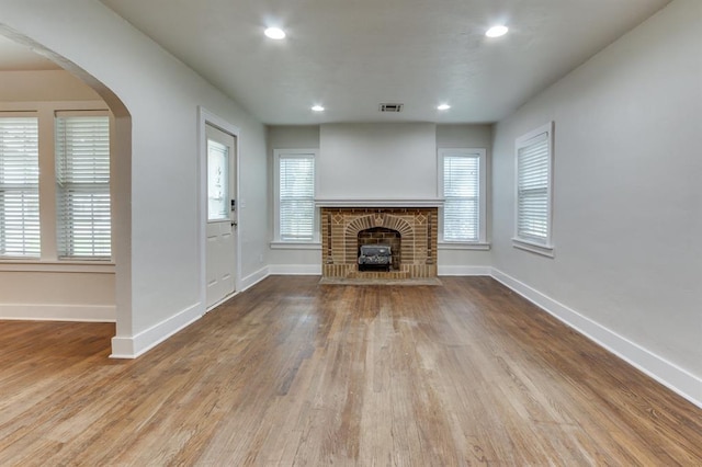 2524 NW 15th St, Oklahoma City, OK 73107 - unfurnished living room with a brick fireplace, wood finished floors, arched walkways, and recessed lighting