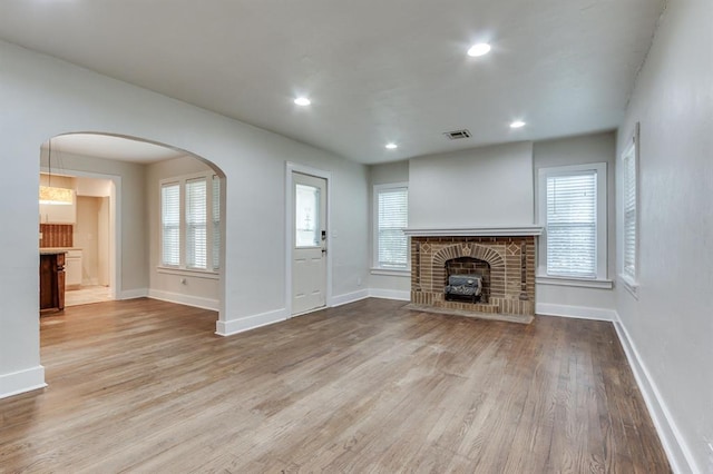 2524 NW 15th St, Oklahoma City, OK 73107 - unfurnished living room with a brick fireplace, wood finished floors, recessed lighting, and arched walkways
