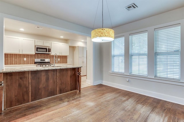 2524 NW 15th St, Oklahoma City, OK 73107 - kitchen featuring appliances with stainless steel finishes, light wood finished floors, light stone countertops, tasteful backsplash, and recessed lighting