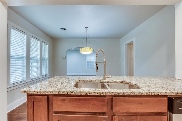 2524 NW 15th St, Oklahoma City, OK 73107 - kitchen with light stone counters, brown cabinetry, pendant lighting, and dark wood-style flooring