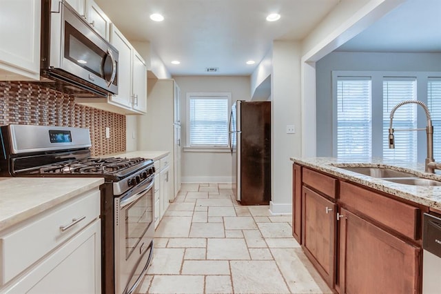 2524 NW 15th St, Oklahoma City, OK 73107 - kitchen with stainless steel appliances, tasteful backsplash, stone tile floors, white cabinetry, and recessed lighting