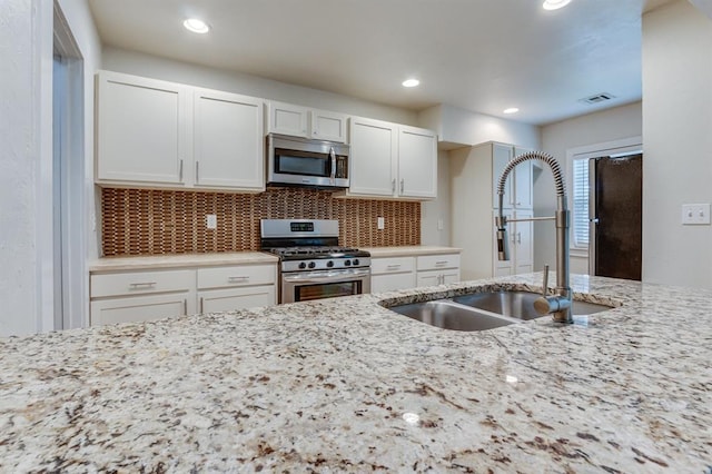 2524 NW 15th St, Oklahoma City, OK 73107 - kitchen featuring stainless steel appliances, light stone counters, white cabinetry, decorative backsplash, and recessed lighting