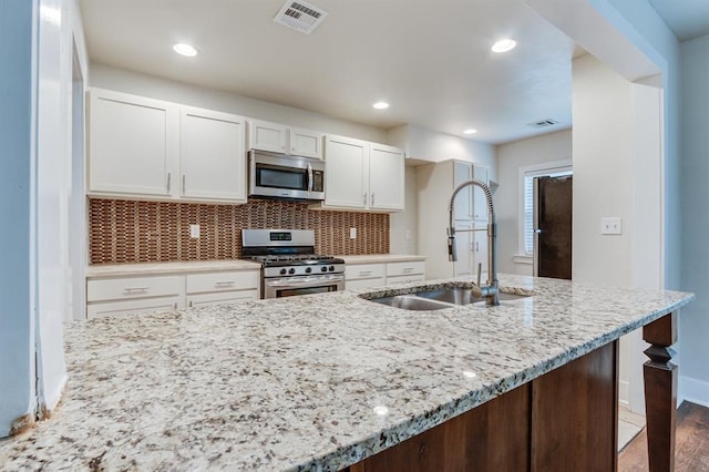 2524 NW 15th St, Oklahoma City, OK 73107 - kitchen featuring stainless steel appliances, white cabinetry, light stone counters, backsplash, and wood finished floors