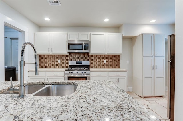2524 NW 15th St, Oklahoma City, OK 73107 - kitchen with stainless steel appliances, white cabinets, light stone countertops, tasteful backsplash, and recessed lighting