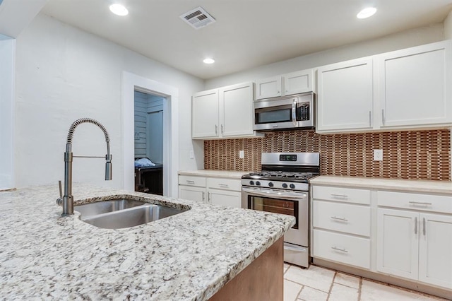2524 NW 15th St, Oklahoma City, OK 73107 - kitchen featuring stainless steel appliances, white cabinetry, light stone counters, recessed lighting, and tasteful backsplash