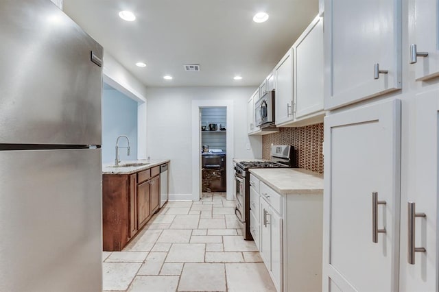 2524 NW 15th St, Oklahoma City, OK 73107 - kitchen with stainless steel appliances, decorative backsplash, recessed lighting, white cabinets, and light stone finish flooring