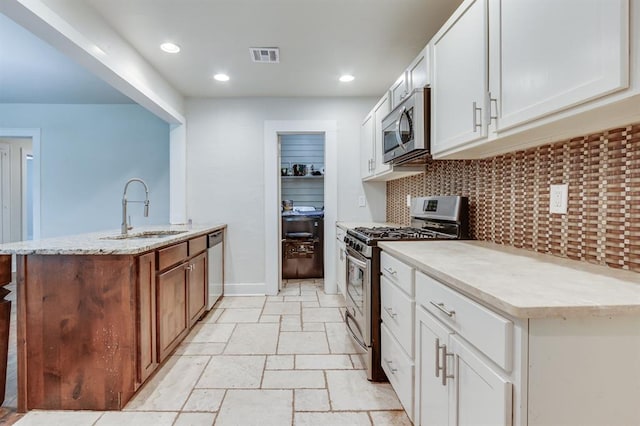 2524 NW 15th St, Oklahoma City, OK 73107 - kitchen with appliances with stainless steel finishes, white cabinetry, light stone counters, tasteful backsplash, and recessed lighting