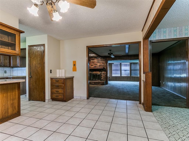 14601 Prairie Ln, Oklahoma City, OK 73165 - kitchen with a ceiling fan, a brick fireplace, light colored carpet, a textured ceiling, and light countertops