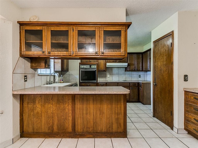 14601 Prairie Ln, Oklahoma City, OK 73165 - kitchen featuring oven, under cabinet range hood, decorative backsplash, light countertops, and stovetop