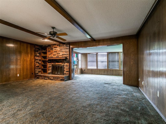 14601 Prairie Ln, Oklahoma City, OK 73165 - unfurnished living room with wood walls, a textured ceiling, ceiling fan, beamed ceiling, and a brick fireplace