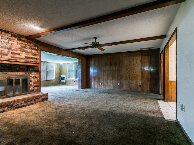 14601 Prairie Ln, Oklahoma City, OK 73165 - unfurnished living room with carpet floors, beamed ceiling, wooden walls, a textured ceiling, and ceiling fan