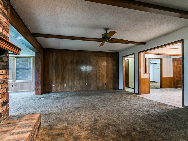 14601 Prairie Ln, Oklahoma City, OK 73165 - unfurnished living room with wood walls, carpet flooring, ceiling fan, and a textured ceiling