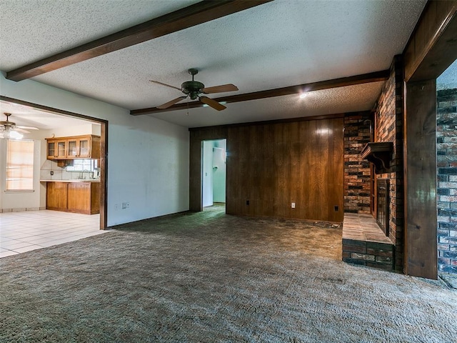 14601 Prairie Ln, Oklahoma City, OK 73165 - unfurnished living room with ceiling fan, a textured ceiling, beam ceiling, carpet floors, and wood walls