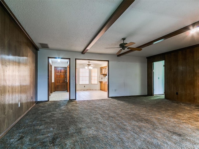 14601 Prairie Ln, Oklahoma City, OK 73165 - unfurnished living room with wooden walls, a textured ceiling, ceiling fan, beamed ceiling, and carpet