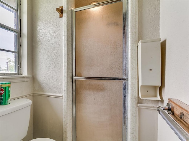 14601 Prairie Ln, Oklahoma City, OK 73165 - bathroom with a textured wall, a shower stall, and a wainscoted wall