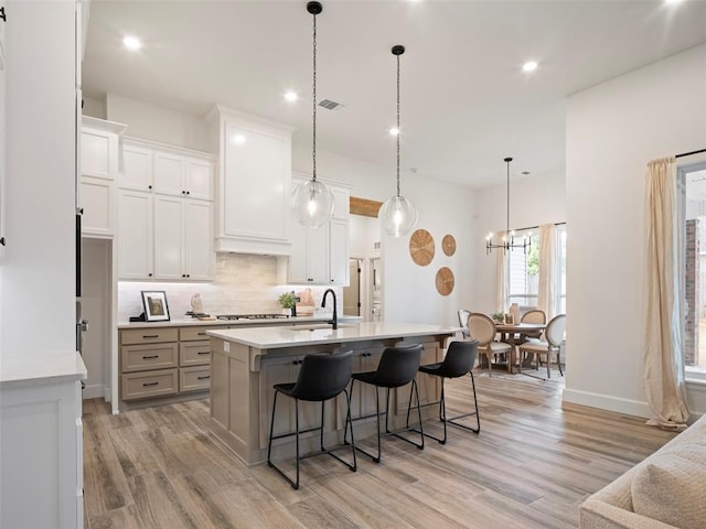 408 Nantucket Blvd, Norman, OK 73071 - kitchen featuring light wood-style flooring, decorative backsplash, light countertops, gas stovetop, and a breakfast bar area