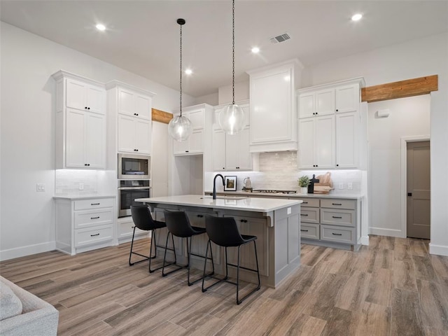 408 Nantucket Blvd, Norman, OK 73071 - kitchen with stainless steel appliances, light wood-style floors, tasteful backsplash, an island with sink, and recessed lighting
