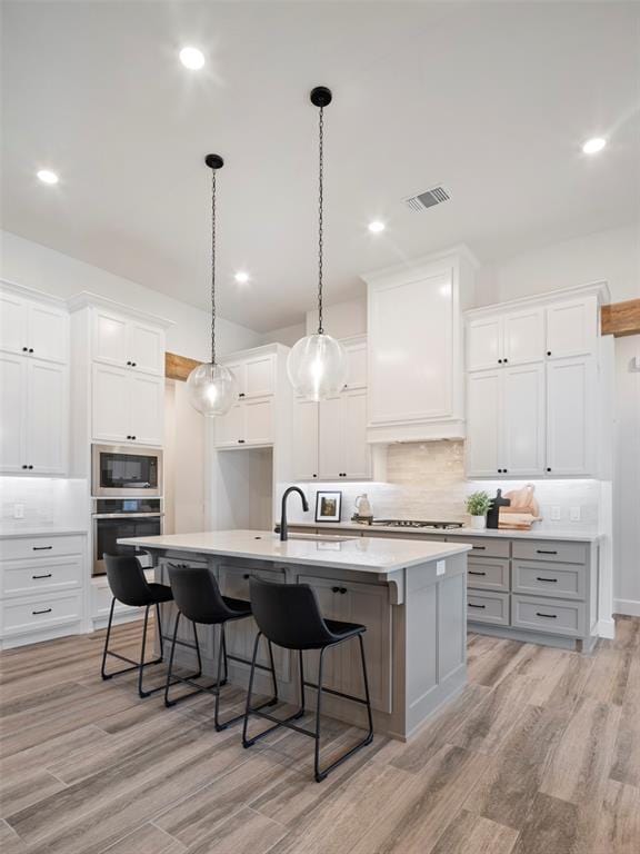 408 Nantucket Blvd, Norman, OK 73071 - kitchen featuring stainless steel oven, built in microwave, a spacious island, light wood-style floors, and decorative backsplash