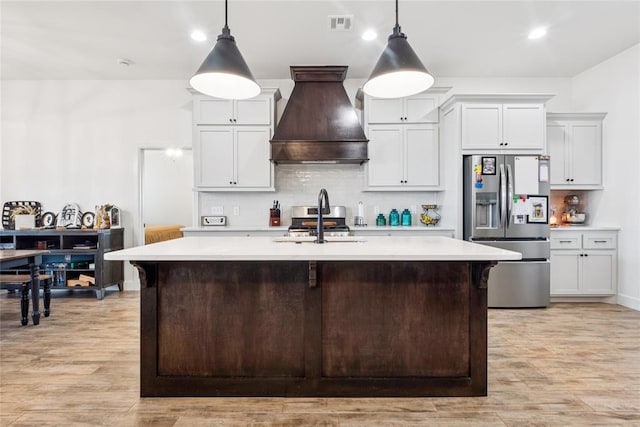 10413 SW 51st St, Mustang, OK 73064 - kitchen with stainless steel appliances, premium range hood, light countertops, light wood finished floors, and decorative backsplash