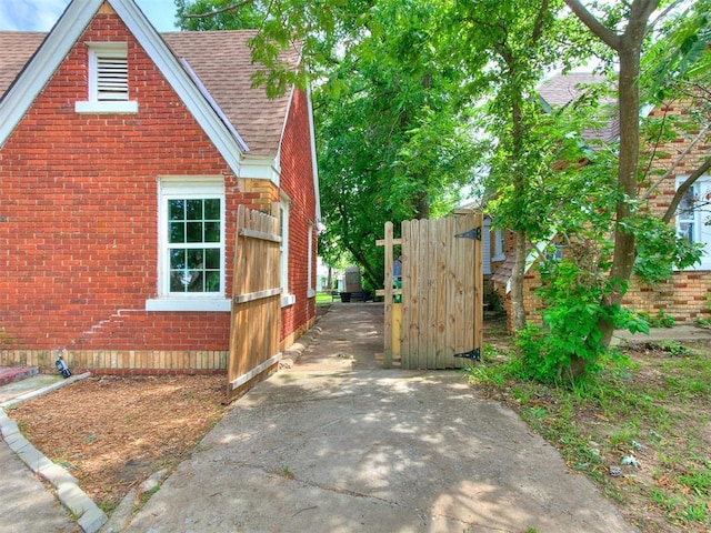 2016 Hardin Dr, Oklahoma City, OK 73111 - view of side of home with roof with shingles, brick siding, and a gate