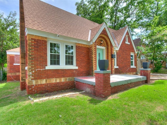 2016 Hardin Dr, Oklahoma City, OK 73111 - tudor-style house featuring roof with shingles, a front yard, and brick siding