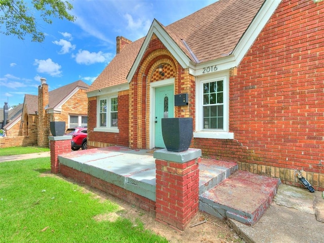 2016 Hardin Dr, Oklahoma City, OK 73111 - view of exterior entry with brick siding, a shingled roof, and a lawn