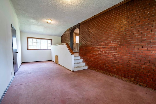 420 E 12th St, Chandler, OK 74834 - unfurnished living room featuring light colored carpet, a textured ceiling, brick wall, stairs, and arched walkways