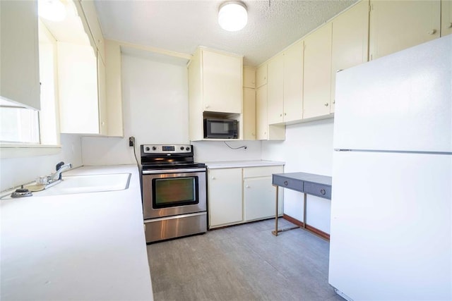420 E 12th St, Chandler, OK 74834 - kitchen featuring freestanding refrigerator, stainless steel range with electric stovetop, black microwave, light wood-style flooring, and light countertops