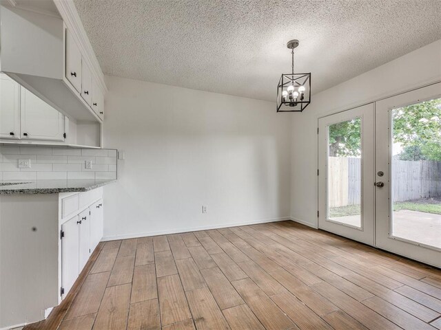 8317 Curtis Ter, Oklahoma City, OK 73132 - unfurnished dining area with a textured ceiling, light wood finished floors, a chandelier, and french doors