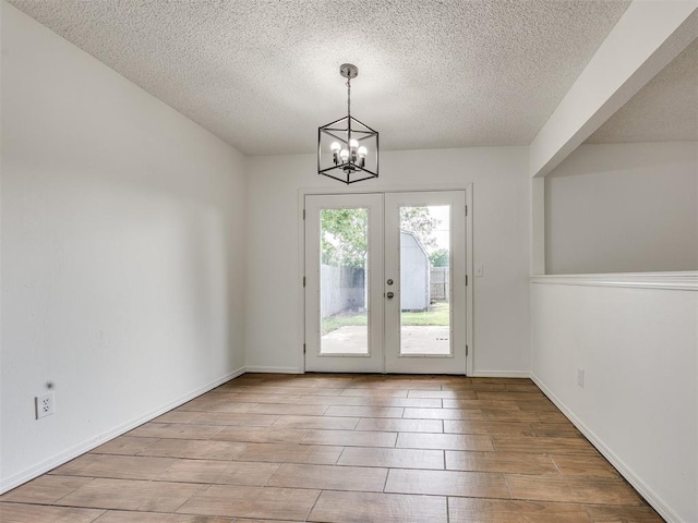 8317 Curtis Ter, Oklahoma City, OK 73132 - unfurnished dining area with a textured ceiling, a chandelier, french doors, and wood finished floors