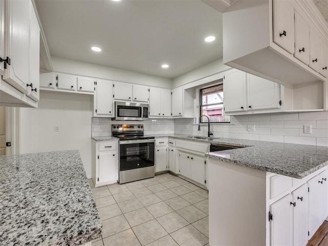 8317 Curtis Ter, Oklahoma City, OK 73132 - kitchen featuring stainless steel appliances, a peninsula, white cabinets, decorative backsplash, and recessed lighting