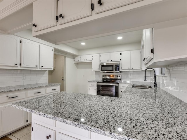8317 Curtis Ter, Oklahoma City, OK 73132 - kitchen featuring appliances with stainless steel finishes, a peninsula, light stone counters, decorative backsplash, and recessed lighting