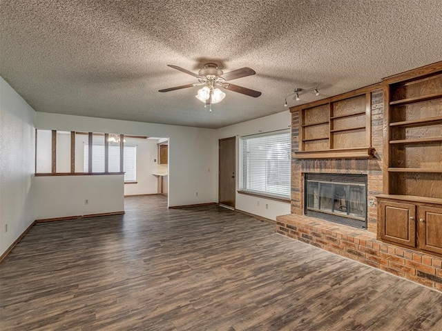 10428 Fairfax Ln, Yukon, OK 73099 - unfurnished living room with a textured ceiling, a brick fireplace, dark wood-type flooring, and a ceiling fan