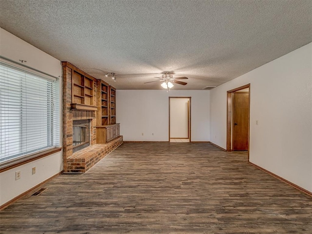 10428 Fairfax Ln, Yukon, OK 73099 - unfurnished living room with ceiling fan, dark wood finished floors, a textured ceiling, a fireplace, and built in shelves