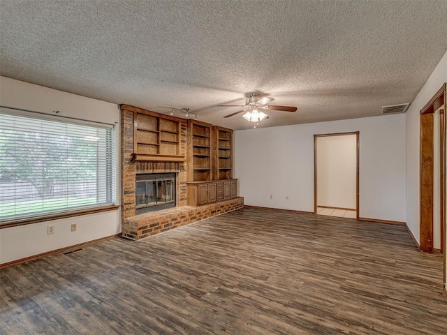 10428 Fairfax Ln, Yukon, OK 73099 - unfurnished living room featuring a ceiling fan, wood finished floors, a brick fireplace, a textured ceiling, and built in features