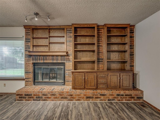 10428 Fairfax Ln, Yukon, OK 73099 - unfurnished living room with a textured ceiling, wood finished floors, and a brick fireplace