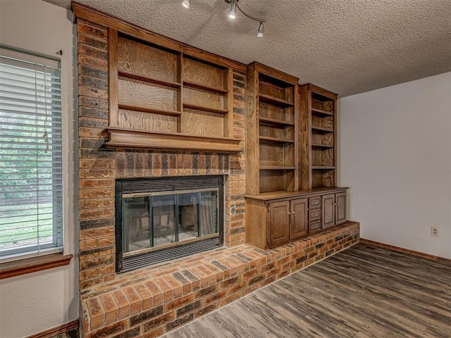 10428 Fairfax Ln, Yukon, OK 73099 - unfurnished living room featuring a textured ceiling, wood finished floors, and a brick fireplace