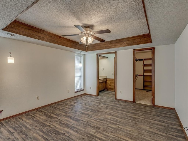 10428 Fairfax Ln, Yukon, OK 73099 - unfurnished bedroom featuring a textured ceiling, wood finished floors, a raised ceiling, a spacious closet, and ensuite bathroom