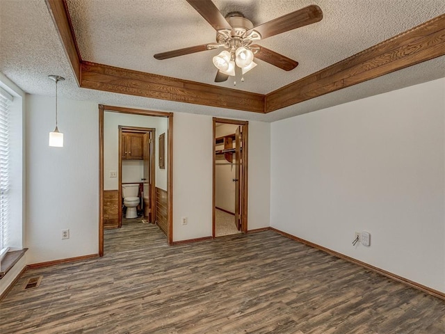 10428 Fairfax Ln, Yukon, OK 73099 - unfurnished bedroom featuring a textured ceiling, wood finished floors, ensuite bathroom, ceiling fan, and a walk in closet