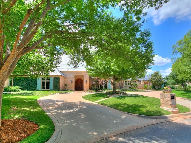 5708 Normandy Ter, Oklahoma City, OK 73142 - view of front of property featuring a front lawn, brick siding, and curved driveway