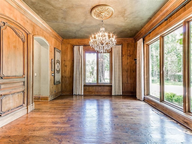 5708 Normandy Ter, Oklahoma City, OK 73142 - unfurnished dining area featuring a chandelier, wood finished floors, ornamental molding, wood walls, and arched walkways