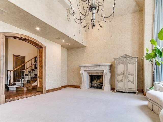 5708 Normandy Ter, Oklahoma City, OK 73142 - unfurnished living room featuring carpet floors, arched walkways, a towering ceiling, a high end fireplace, and stairs
