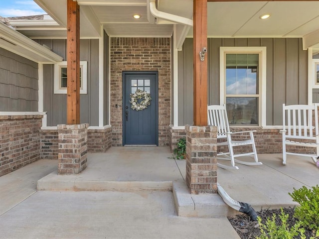 18716 Lazy Grove Dr, Edmond, OK 73012 - entrance to property featuring board and batten siding, covered porch, and brick siding