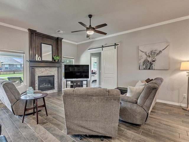 18716 Lazy Grove Dr, Edmond, OK 73012 - living area with a barn door, crown molding, a ceiling fan, wood finished floors, and a fireplace