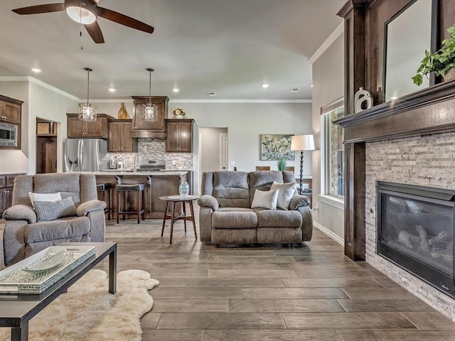 18716 Lazy Grove Dr, Edmond, OK 73012 - living room featuring ceiling fan, recessed lighting, dark wood-style floors, a stone fireplace, and ornamental molding