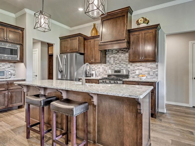 18716 Lazy Grove Dr, Edmond, OK 73012 - kitchen with stainless steel appliances, decorative backsplash, a center island with sink, light stone counters, and ornamental molding