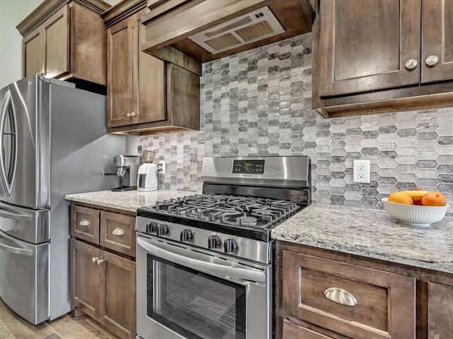 18716 Lazy Grove Dr, Edmond, OK 73012 - kitchen featuring stainless steel appliances, ventilation hood, light stone countertops, and tasteful backsplash