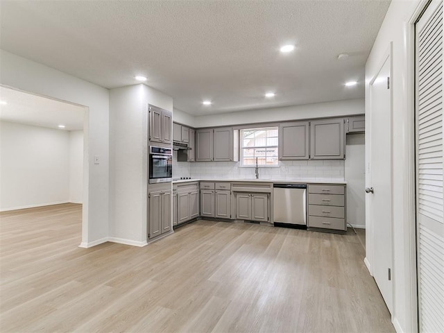 502 Walnut Ave, Yukon, OK 73099 - kitchen featuring appliances with stainless steel finishes, gray cabinets, light wood finished floors, backsplash, and recessed lighting
