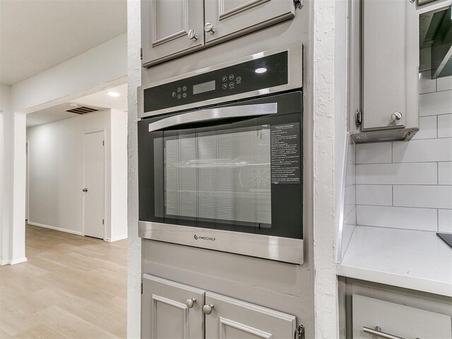502 Walnut Ave, Yukon, OK 73099 - kitchen view of stainless steel oven, light wood-style flooring, gray cabinets, and light countertops